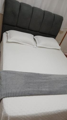 a white bed with a black headboard and two pillows at Estúdio no Vieiralves in Manaus