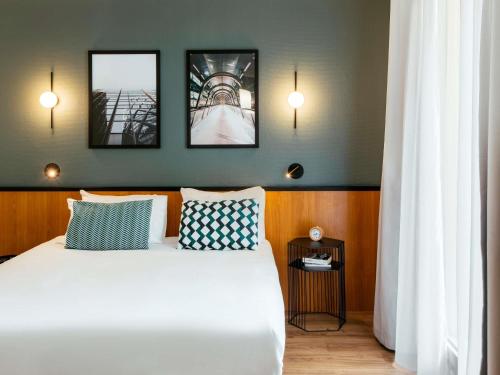 a bedroom with a bed with three pictures on the wall at Aparthotel Adagio La Défense Le Parc in Courbevoie