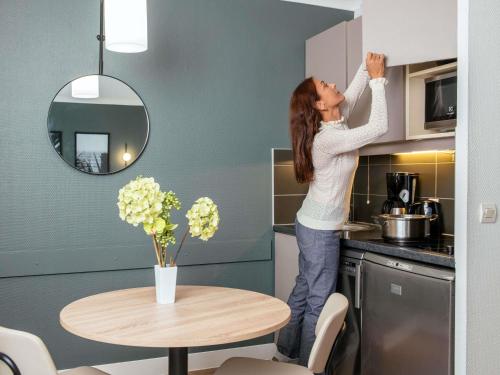 a woman is standing in a kitchen next to a table at Aparthotel Adagio La Défense Le Parc in Courbevoie