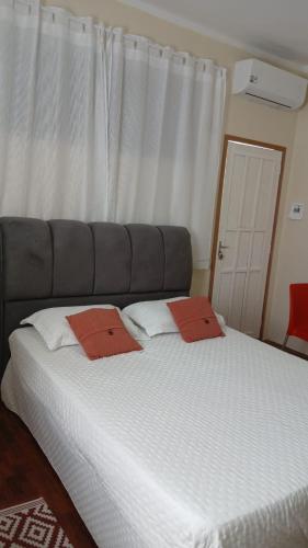 a bedroom with a large bed with two red pillows at Estúdio no Vieiralves in Manaus