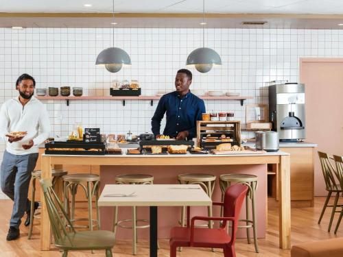 two men standing in a kitchen preparing food at Aparthotel Adagio La Défense Le Parc in Courbevoie