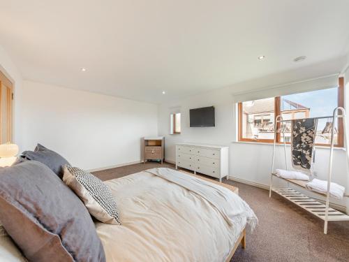 a white bedroom with a bed and a window at The Beaches in Berwick-Upon-Tweed