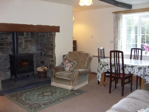 a living room with a fireplace and a table and chairs at East Hook Holiday Cottages - Daisy Cottage in Okehampton