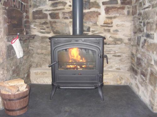 a stove in a stone fireplace in a room at East Hook Holiday Cottages - Daisy Cottage in Okehampton