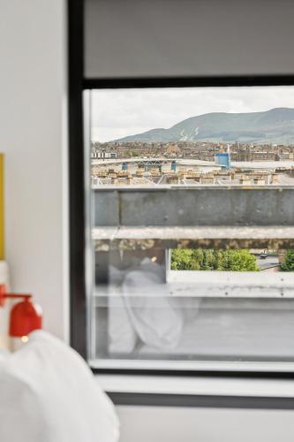 a person looking out of a window at a city at Garner Hotel Edinburgh - Haymarket by IHG in Edinburgh