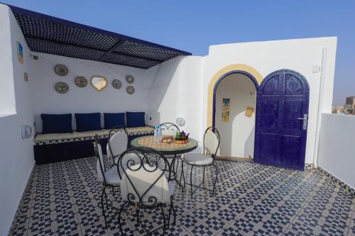 a room with a table and chairs and a blue door at Riad dar HAPPY NOCHE in Essaouira