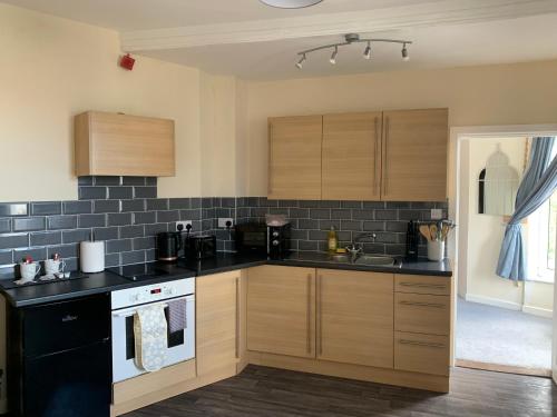 a kitchen with wooden cabinets and black appliances at 155 studio 6 - Uplands - Smart Tv in Swansea