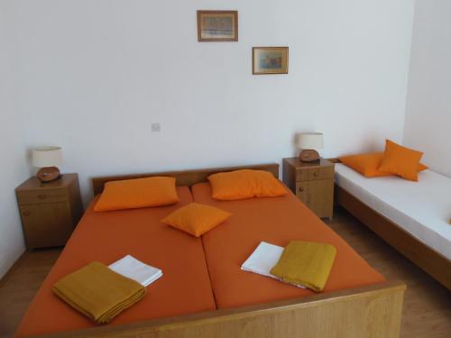 a large orange bed in a room with two beds at Apartments Skipper in Seget Vranjica