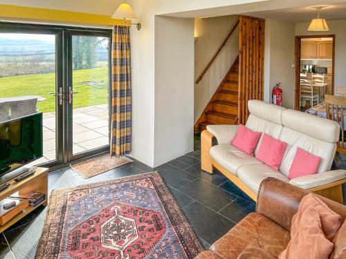 a living room with a couch and a tv at Ty Nant-Oxl in Gwynfe