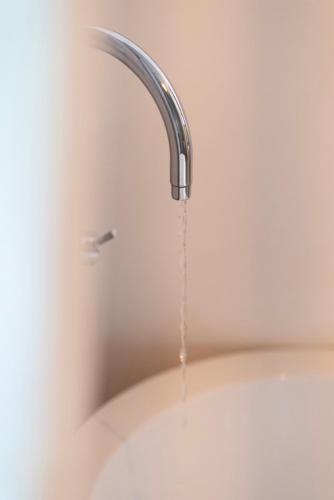 a silver faucet with water coming out of it at Savera Beach Houses in Jambiani