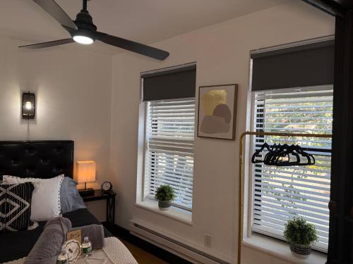 a bedroom with a ceiling fan and two windows at Boutique Studio Apartment on Grand Ave in Englewood