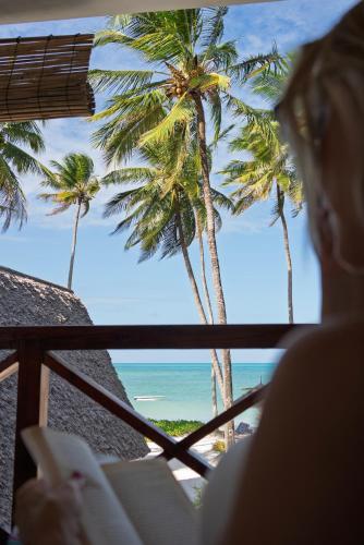 a woman looking out at the ocean and palm trees at Savera Beach Houses in Jambiani