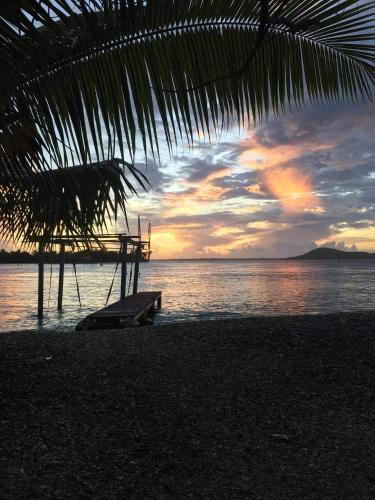 a bench sitting on the beach with a sunset at Tiapaa Village in Maupiti