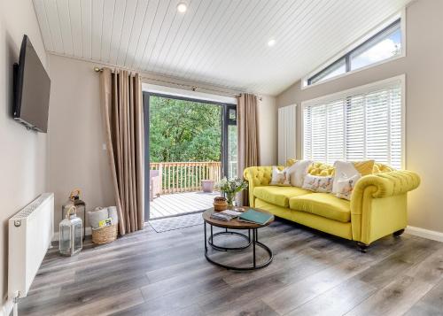 a living room with a yellow couch and a table at Charlesworth Lodges in Glossop
