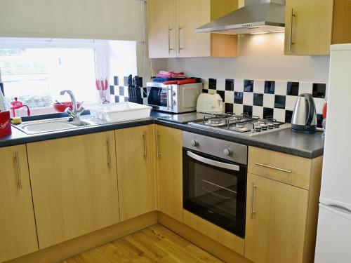 a kitchen with a sink and a stove top oven at Cheviot Cottage in Belford