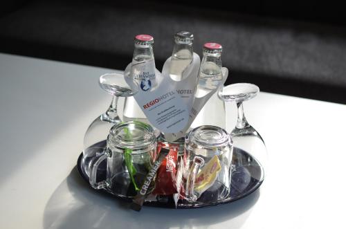 a tray with three bottles and glasses on a table at REGIOHOTEL Schanzenhaus Wernigerode in Wernigerode