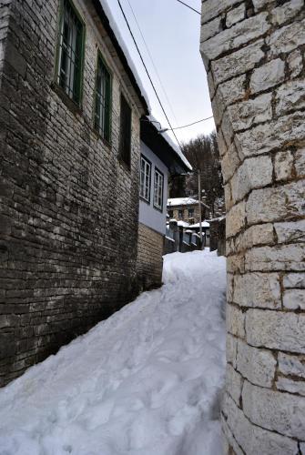 a brick building with snow on the side of it at Gaia Guesthouse in Dilofo