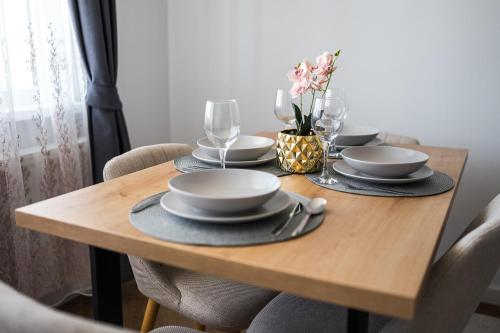 a wooden table with plates and wine glasses on it at Sky9 Apartment in Odorheiu Secuiesc