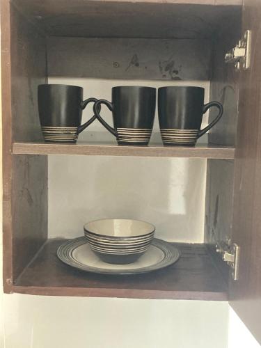 a shelf with three cups and plates on it at Pamito Sunny Paradise in Diani in Diani Beach