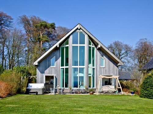 ein Haus mit großen Glasfenstern auf einem Hof in der Unterkunft Quantock Lodge in Chillington