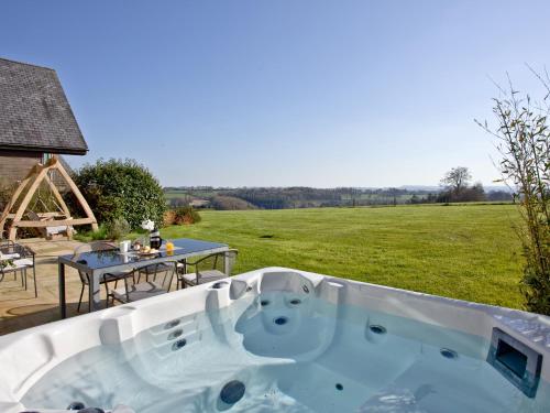 eine Whirlpool-Badewanne im Hof mit Tisch in der Unterkunft Quantock Lodge in Chillington