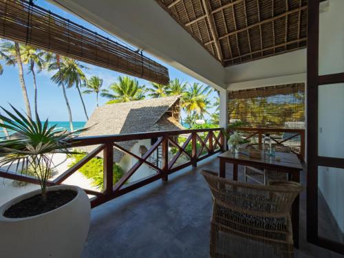 a room with a balcony with a view of the ocean at Savera Beach Houses in Jambiani