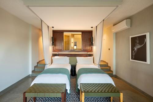 a row of four beds in a room with stairs at The David Livingstone Safari Lodge & Spa in Livingstone