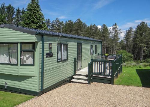 a green tiny house with a porch and a deck at Springhouse Country Park in Slaley