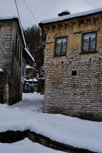 a brick building with snow in front of it at Gaia Guesthouse in Dilofo