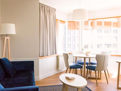 a living room with a couch and a table with chairs at Aparthotel Adagio Paris Centre Tour Eiffel in Paris