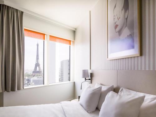 a bedroom with a bed and a window with the eiffel tower at Aparthotel Adagio Paris Centre Tour Eiffel in Paris