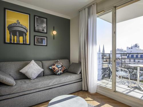 a living room with a couch and a balcony at Aparthotel Adagio Paris Buttes Chaumont in Paris