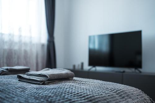 a bedroom with a bed with towels and a tv at Sky9 Apartment in Odorheiu Secuiesc