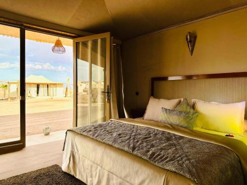 a bedroom with a bed with a view of the desert at Agafay Yes We Camp Restaurant & Spa in Aït Mazou