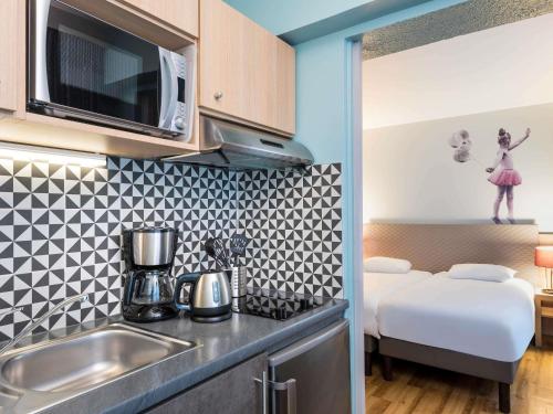 a small kitchen with a sink and a microwave at Aparthotel Adagio Paris Montmartre in Paris