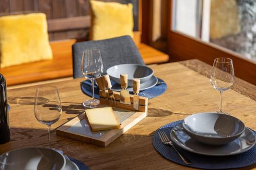 a wooden table with plates and wine glasses on it at Le Chamois l Ski-out l Standing in Siviez