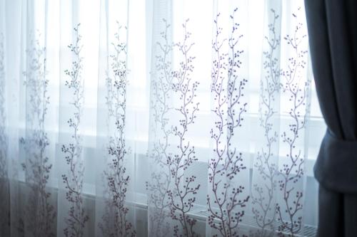a window with white curtains with plants on it at Sky9 Apartment in Odorheiu Secuiesc