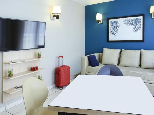 a living room with a red suitcase and a couch at Aparthotel Adagio Monaco Monte Cristo in Beausoleil