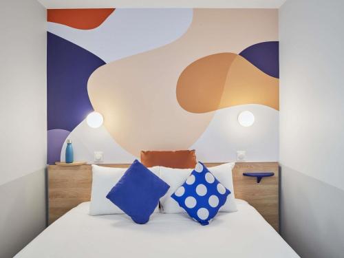 セリにあるAparthotel Adagio Val d'Europe près de Disneyland Parisの白いベッドと青い枕のある寝室
