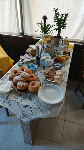 a table with a bunch of donuts and plates on it at Tidale Host house B&B in Alghero