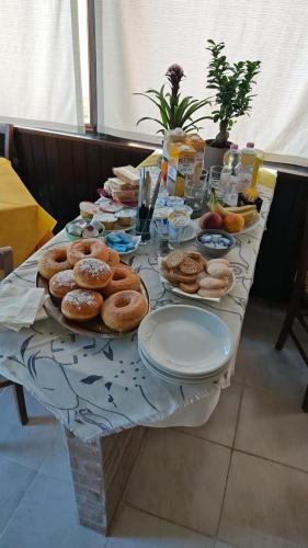 a table with a bunch of donuts and plates on it at Tidale Host house B&B in Alghero