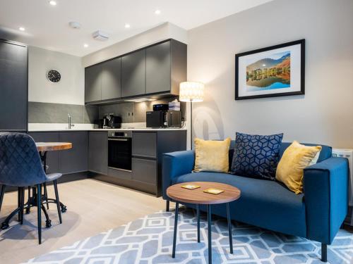 a living room with a blue couch and a kitchen at The Flowing River in Ulverston