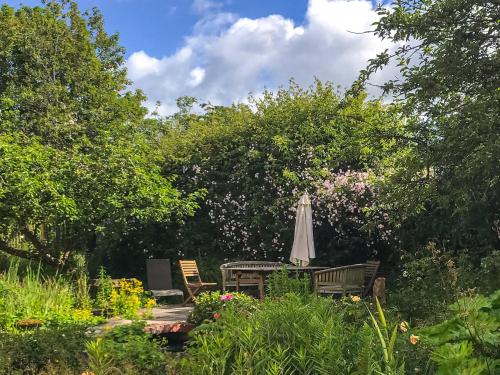 an umbrella and a table and chairs in a garden at Ynywsen Dairy Flat in Llanfynydd