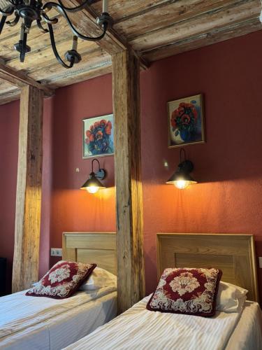 two beds in a room with red walls at Pilsberģu krogs in Jūrkalne