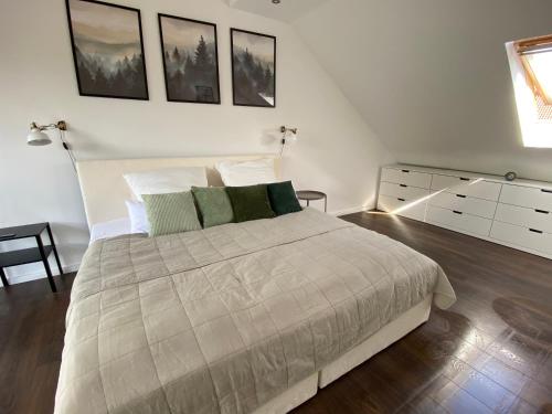 a white bedroom with a large bed and a dresser at EinKlang - Familienidyll in Seesen