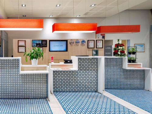 a waiting room with blue and white seats and a tv at Ibis Tanger City Center in Tangier