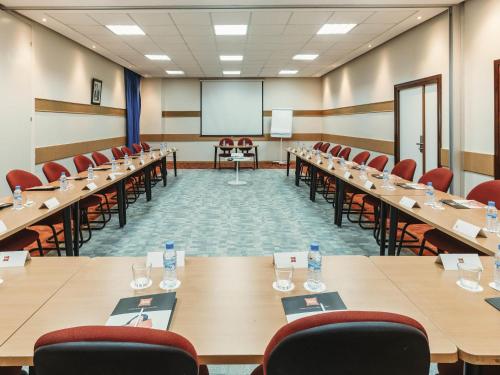 a conference room with tables and chairs and a screen at Ibis Tanger City Center in Tangier
