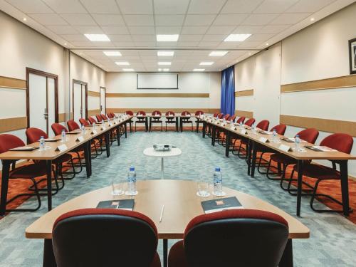 a conference room with tables and chairs and a projector at Ibis Tanger City Center in Tangier