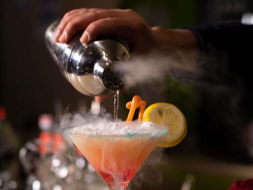 a person is pouring a drink into a cocktail at Ibis Tanger City Center in Tangier