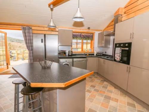 a large kitchen with a counter top and appliances at Alpaca cabin-mountain view-hot tub-rural retreat in Llanbrynmair